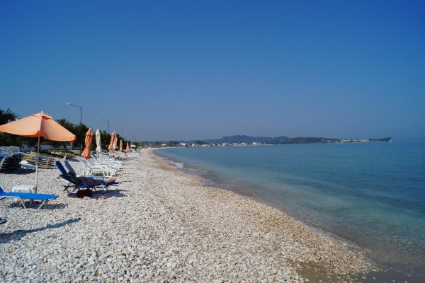 A blue sea under a blue sky and some bar's loungers on the Arachavi pebble beach.
