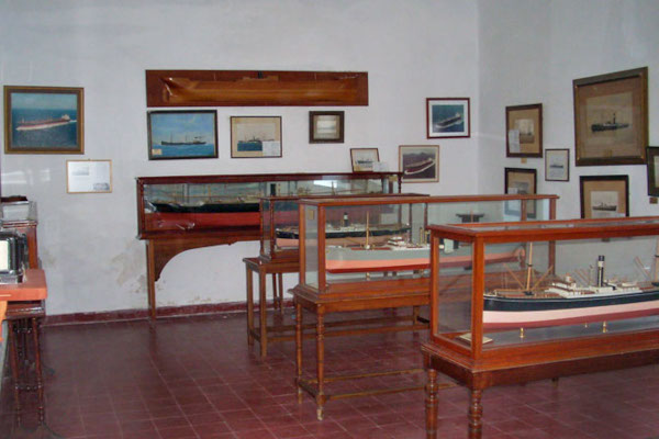 A picture of one of the rooms of the Andros Maritime Museum with displays and exhibits hanging on the wall.