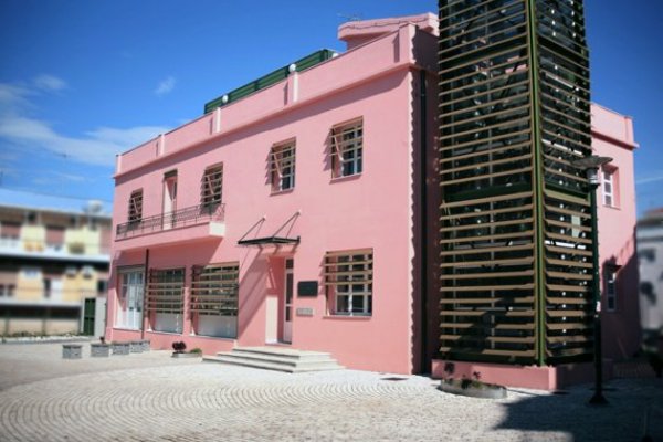 Municipal Art Gallery of Arta - G. Moralis is a two-story pink building with covered external stairs.