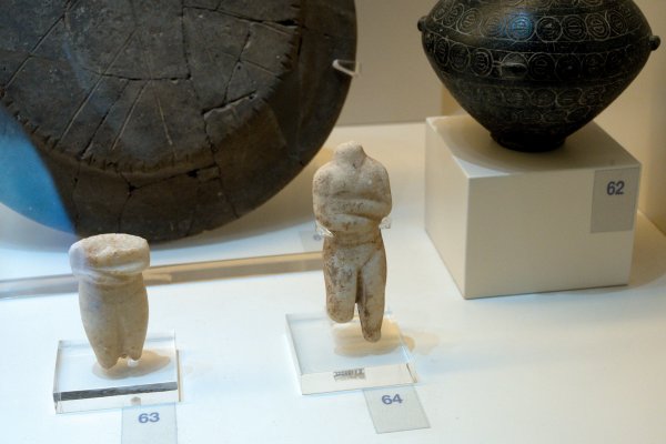 Two white statue figurines in front of two black utensils marked with numbers.