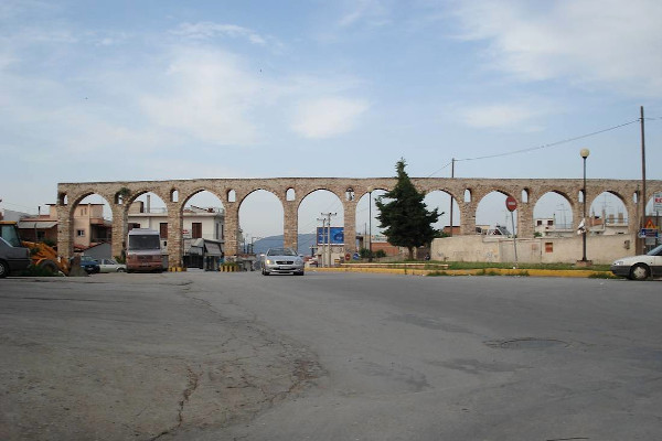 A photo of the arches of the Roman Aqueduct of Chalkida and a few parked cars.