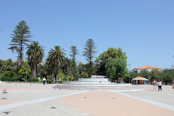 A photo showing the Main Square (Vounakiou) of Chios town with palm trees and other plants.