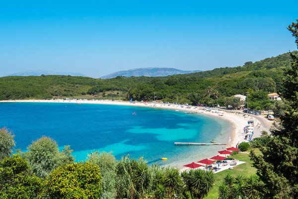 The Avlaki beach between blue waters and lush green forest at Kassiopi, Corfu.