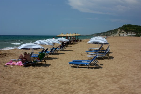 The wide Marathias sandy beach and people enjoying on sunbeds.