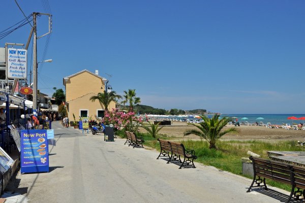 A street with benches on one side and restaurants on the other at Roda beach, Corfu.