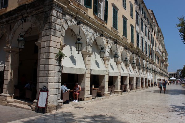 A picture of the Liston pedestrian street in Corfu with people enjoying their coffee at the local cafeterias.