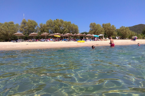 A picture taken from the sea depicts people in the water and umbrellas and sunbeds at the Develiki Beach. 