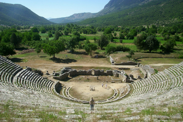 Panoramic view of the ancient theater of Dodoni with the green valley and the surrounding mountains in the background.