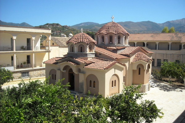 A monastery with two domes and a tiled roof surrounded by monks' houses.