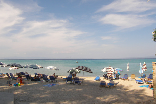 People with umbrellas and sunbeds at the Hanioti Beach in Halkidiki.