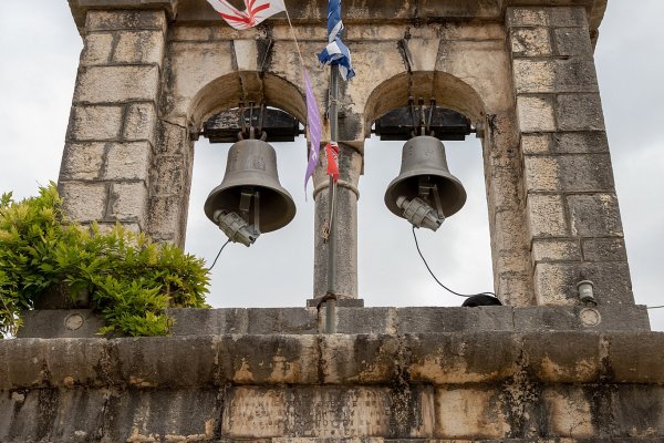 Two church bells and small colorful flags hang on the belfry of Cassopetra church.
