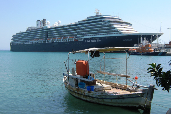 A big cruise ship moored at Katakolo port as a small fishing boat is anchored by its coast.