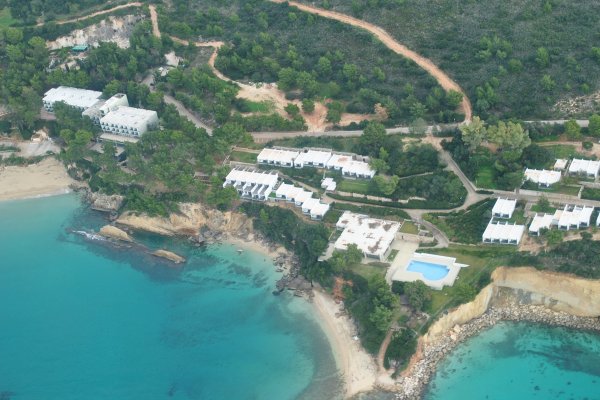 An aerial picture of two beaches on different bays and a hotel built on top the overlooking cliff.