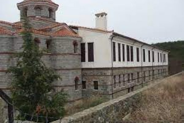 The St. Maximus of Kafsokalyvia Greek-Orthodox monastery built of grey stone behind a short wall.