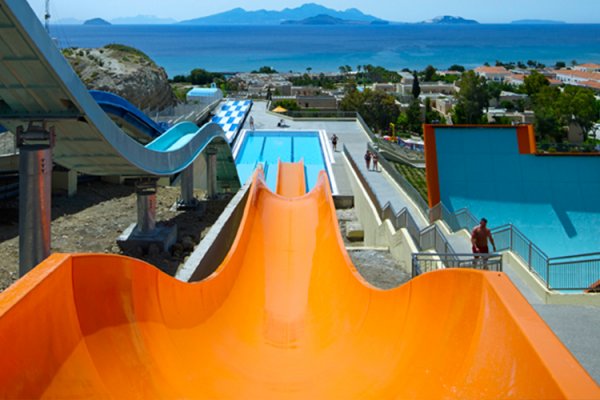 A yellow and a blue waterslide with a view over islands in the horizon leading into a pool.