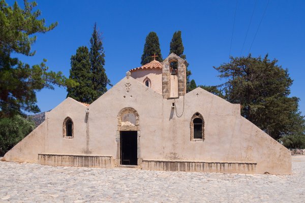 A light-brown church with a sharp-cornered façade, a dome, and a small belfry - the Panagia Kera Church, Kritsa.