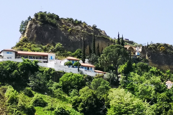 The convent of Panagia Kremasti at Lanthi built on a rock's edge surrounded by dense vegetation.