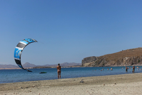 A picture of the beach of Chavouli including some people and kite surfing.