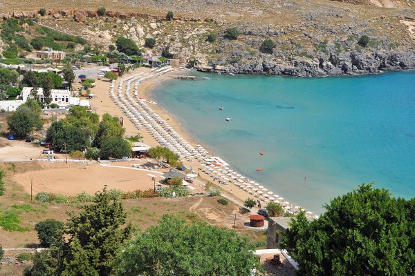 A panoramic picture of the Megali (Large) Beach of Lindos filled with umbrellas.