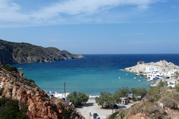 A bay with turquoise waters and a small settlement with white houses on its right arm, Firopotamos Beach, Melos.