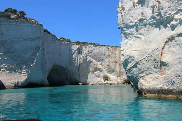 An image showing huge cliffs, caves, and turquoise waters of Kleftiko.