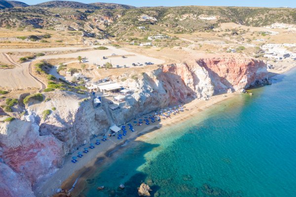 An aerial picture of red and yellow cliffs and green-blue sea at Tourlos, Melos.