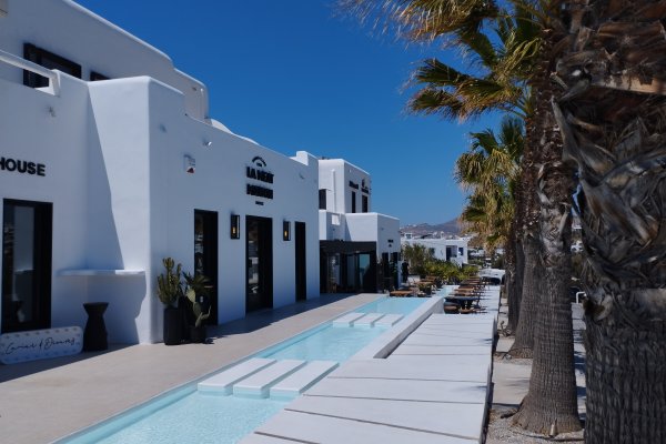 The front face of the MyMall Mykonos with a small canal and a row of trees.