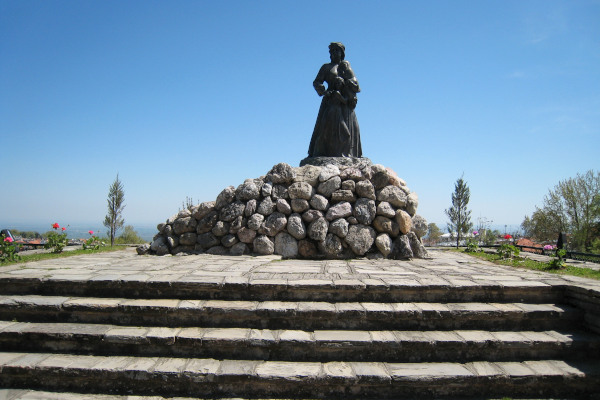 The Massacre memorial of Naousa is a statue of a woman with two children in her arms standing on a pile of rocks.