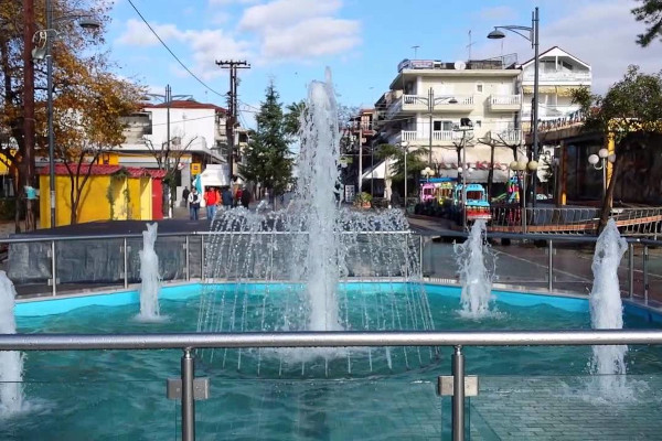 The fountain at the Central Square of Nea Kalikratia with residential buildings in the background.