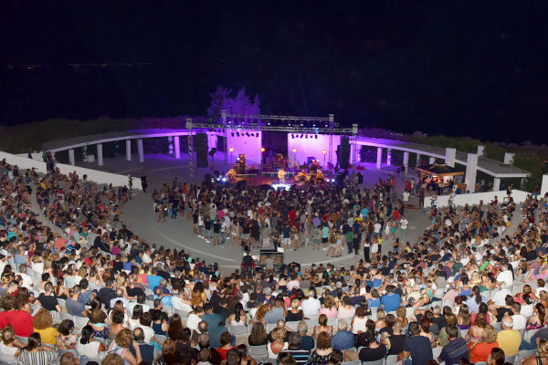 The audience and the band on the stage during a concert in the amphitheater of Nea Moudania.