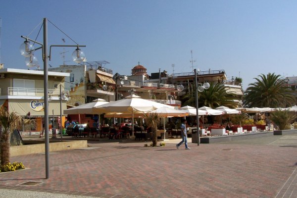 A part of the promenade by the port of Nea Moudania with tavernas and dining tables.
