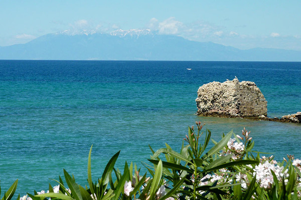 Remains of Potidea's ancient port with the blue sea and a snowy mount Olympus in the background.