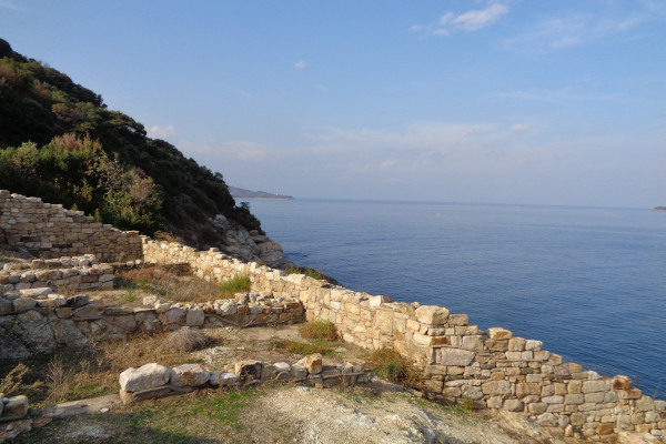 The remnants of the Stagira archaeological site with the deep blue of the Aegean Sea in the background.