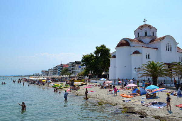 A picture showing the beach of Paralia Katerini with a church and buildings of the homonymous settlement in the background.