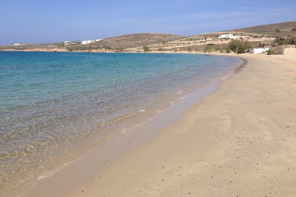 The golden landscape of Krios beach without people, Paros, and hills in the background.
