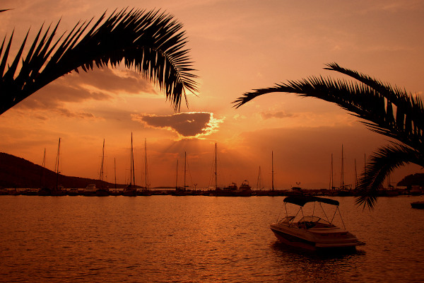 A picture showing a tourist boat and many other sailing boats in the marina of Plataria during an evening.