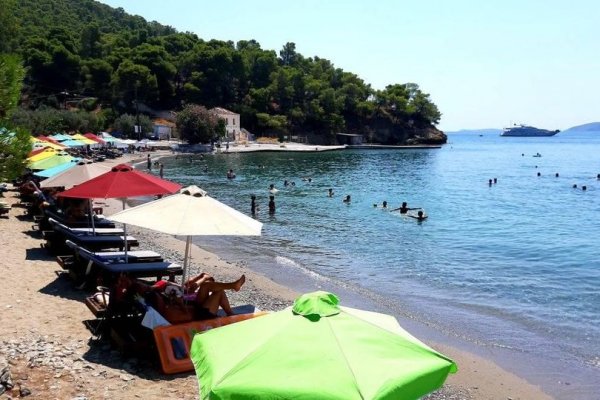 A photo of umbrellas, sun beds and people enjoying at the Monastiri Beach of Poros.