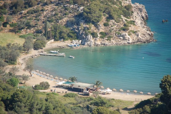 A panoramic photo showing the beach of Vagionia on Poros by a rocky hill.