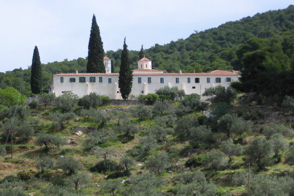 A picture of the exterior of the «Zoodohos Pigi» Monastery in Poros in lush vegetation.