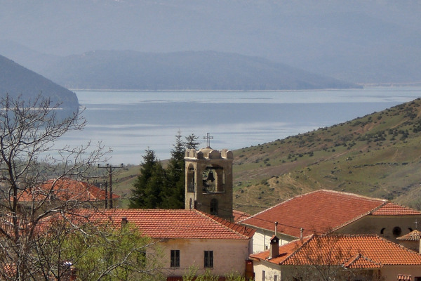 The belfry and some houses of Agios Germanos village with the Prespa lake in the background.