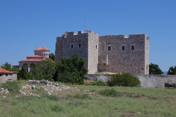 The Tower of Lykourgos Logothetis in Samos is a two-story stone-built fort by a grassy field.