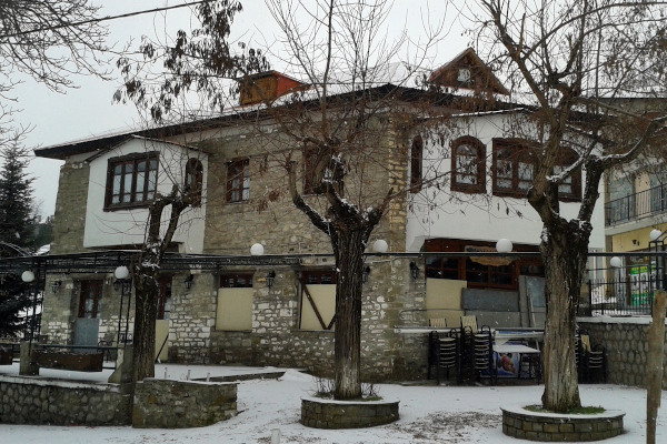 A building of typical mountain architecture at a snowy square of Samarina.