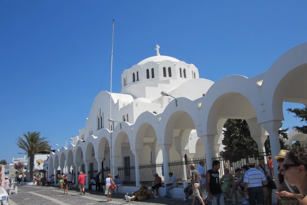 A series of white arches and the white dome of the Metropolitan Cathedral of Fira.