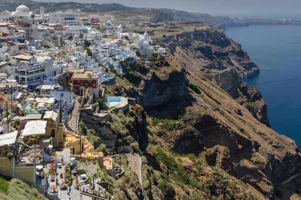 An overview of the Fira village in Santorini with little white houses and a steep cliff. 
