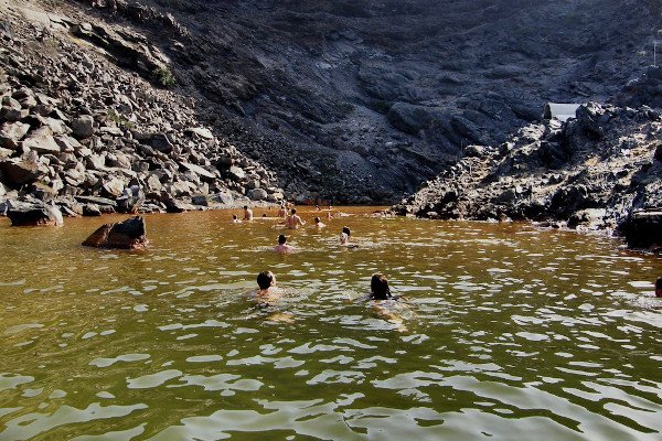 Boat cruise guests swimming in the hot spring waters of Palea Kameni of Santorini.