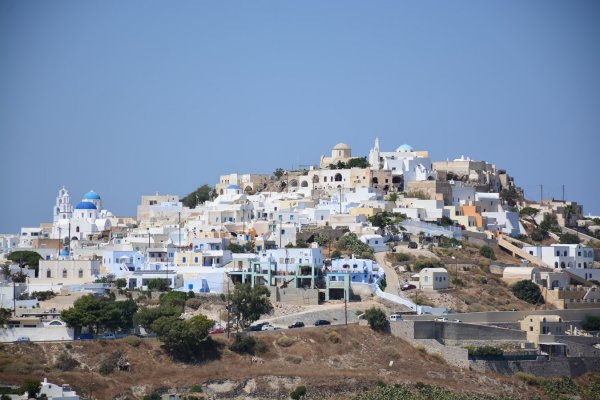 A hill is covered with white houses and a few blue church domes.