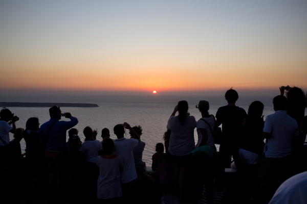 People staring and taking photos of the magical sunset in Santorini.
