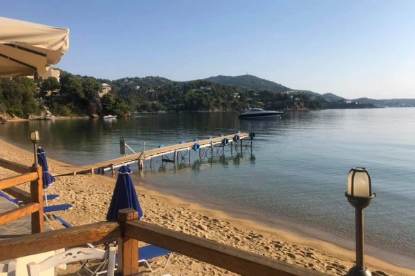 A picture of a small wooden pier over the sea at Kanapitsa beach, Skiathos, taken from a beach bar.