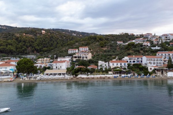 A developed beach, the sea, and buildings, mostly hotels, on a green hill at Megali Ammos.