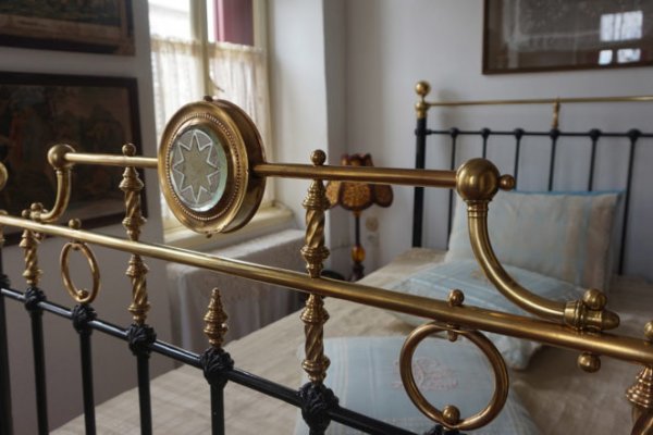 A bed's elaborate footboard in a room with old-school decoration in the House in Skiathos.